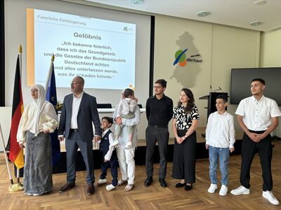 Verschiedene Menschen aus unterschiedlichen Ländern legen ihr Gelöbnis zur Einbürgerung ab.