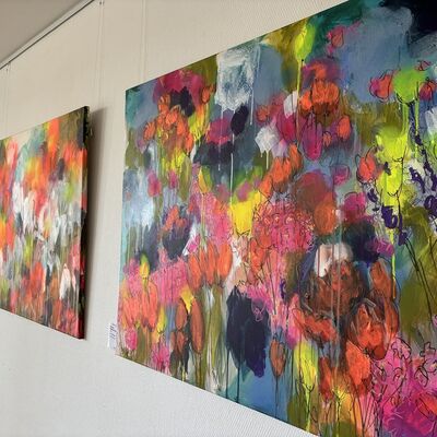 Großformatige, farbenfrohe Leinwände hängen an einer Wand.
