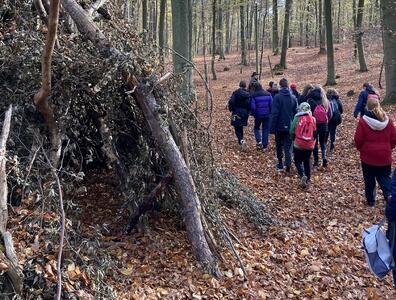 Jugendliche bei einem Waldspaziergang im Herbst inmitten vieler heruntergefallener Blätter.