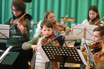 Mehrere Kinder spielen konzentriert Violine.