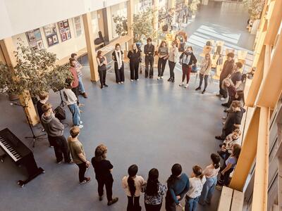 Viele Kinder, Jugendliche und junge Erwachsene stehen im Kreis und besprechen etwas.