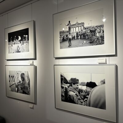 Vier Schwarz-Weiß-Fotografien aus der Zeit des Mauerfalls hängen eingerahmt an einer Wand.