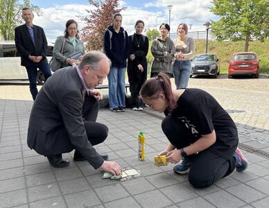 Holger Mittelstädt, Dezernent für Bildung, Kultur und Sport beim Landkreis Oberhavel (links im Bild), putzt gemeinsam mit einer Schülerin der Stolperstein-AG des Louise-Henriette-Gymnasiums  die Gedenkmessingtafeln. 