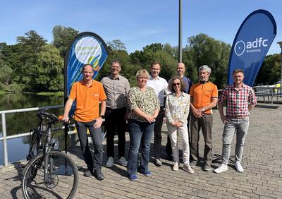Acht Teilnehmerinnen und Teilnehmer der Gesprächsrunde stehen in Oranienburg am Bollwerk. Ein Mann hält ein Fahrrad.