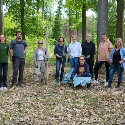 Neun Personen stehen im Wald und lächeln in die Kamera.