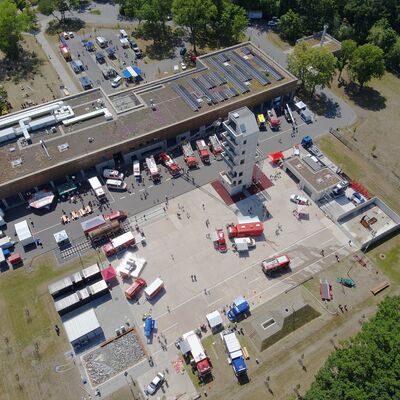 Das Bild zeigt eine Luftaufnahme des Technik- und Ausbildungszentrums (TAZ) mit zahlreichen Einsatzfahrzeugen und Personen.