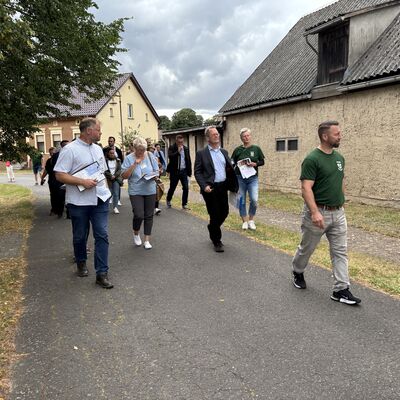 Gruppenfoto von Männern und Frauen auf einem Dorfweg.