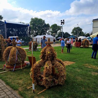 Eine Bühne und eine geschmückte Festwiese mit Sonnenschirmen und vereinzelten Menschen im Hintergrund.