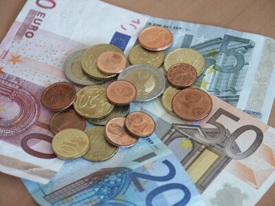 Geldscheine und Münzen liegen gehäuft übereinander. 