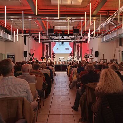 Vollbildaufnahme des Großen Saals in der Kulturfuge Oberhavel: zu sehen ist ein großer Teil des Publikums von Hinten sowie die Bühne.