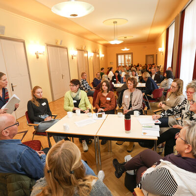 Teilnehmerinnen und Teilnehmer der 3. Kinder- und Jugend-Gesundheitskonferenz sitzen in Tischgruppen beim Workshop 2 mit Frau Dr. med. Andrea Tschirch.
