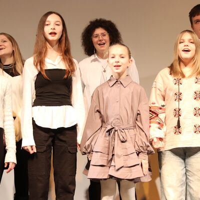 Jungen und Mädchen im Chor auf einer Bühne.