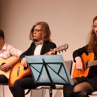 Drei Jungen mit Gitarren auf einer Bühne.