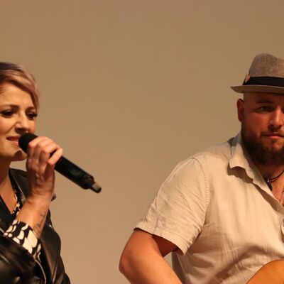 Eine Frau mit Mikrofon und ein Mann mit Gitarre.