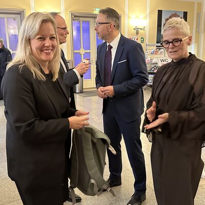 Männer und eine Frau auf einem Stehempfang bei einer Begrüßung.