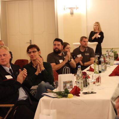 Menschen sitzen an einer festlich gedeckten Tafel.