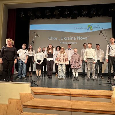 Jungen und Mädchen im Chor auf einer Bühne.