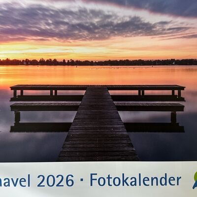 Bild eines Stegs an einem See bei Sonnenaufgang. In blauer Schrift steht unterhalb des Bildes: Oberhavel 2026 Fotokalender. Rechts daneben das offizielle Logo vom Landkreis Oberhavel. 