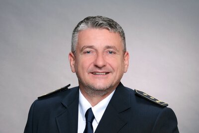 Ein Mann Mitte bis Ende 50 mit grauen, kurzen Haaren in amtlicher Uniform und mit Reverskragen.