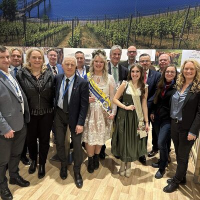 M&auml;nner und Frauen stehen in Zweierreihen auf einem Messestand auf der Gr&uuml;nen Woche.