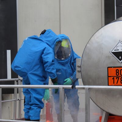 Einsatzkr&auml;fte der Feuerwehr, arbeitend unter Vollschutz und in einem Chemikalienschutzanzug, am dargestellten besch&auml;digtem Beh&auml;lter und bei simuliertem Austreten eines Gefahrstoff, im Rahmen der &Uuml;bung.