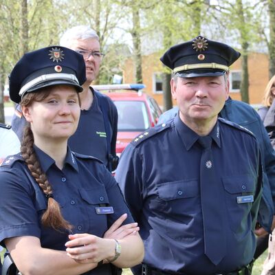 Im Vordergrund: Eine junge Frau mit langem, geflochtenen braunem Zopf in Polizeiuniform. Neben ihr ein &auml;lterer Mann mit graumeliertem Haar und ebenfalls in Uniform der Bundespolizei.