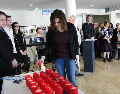 Eine Schülerin entzündet Kerzen bei der Ausstellungseröffnung der Jüdischen Gemeinde Landkreis Oberhavel in der Kreisverwaltung