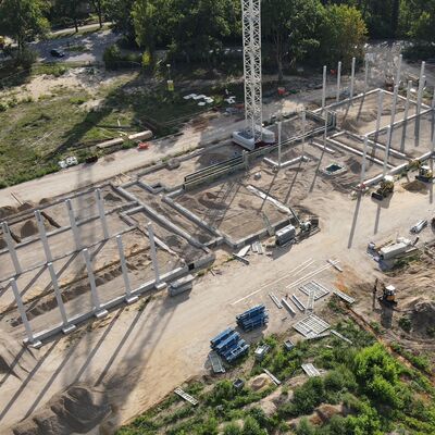 Luftbild von schräg oben. Auf dem Baufeld sind die ersten Säulen/ Stützen für den Rohbau zu erkennen.