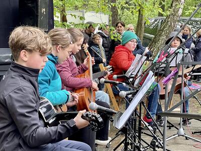 Vier Kinder spielen Gitarre auf einer Bühne.